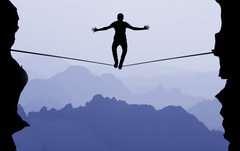 Person walking a tightrope between two cliffs — a metaphor for the high-pressure balancing act of a Performer procrastinator